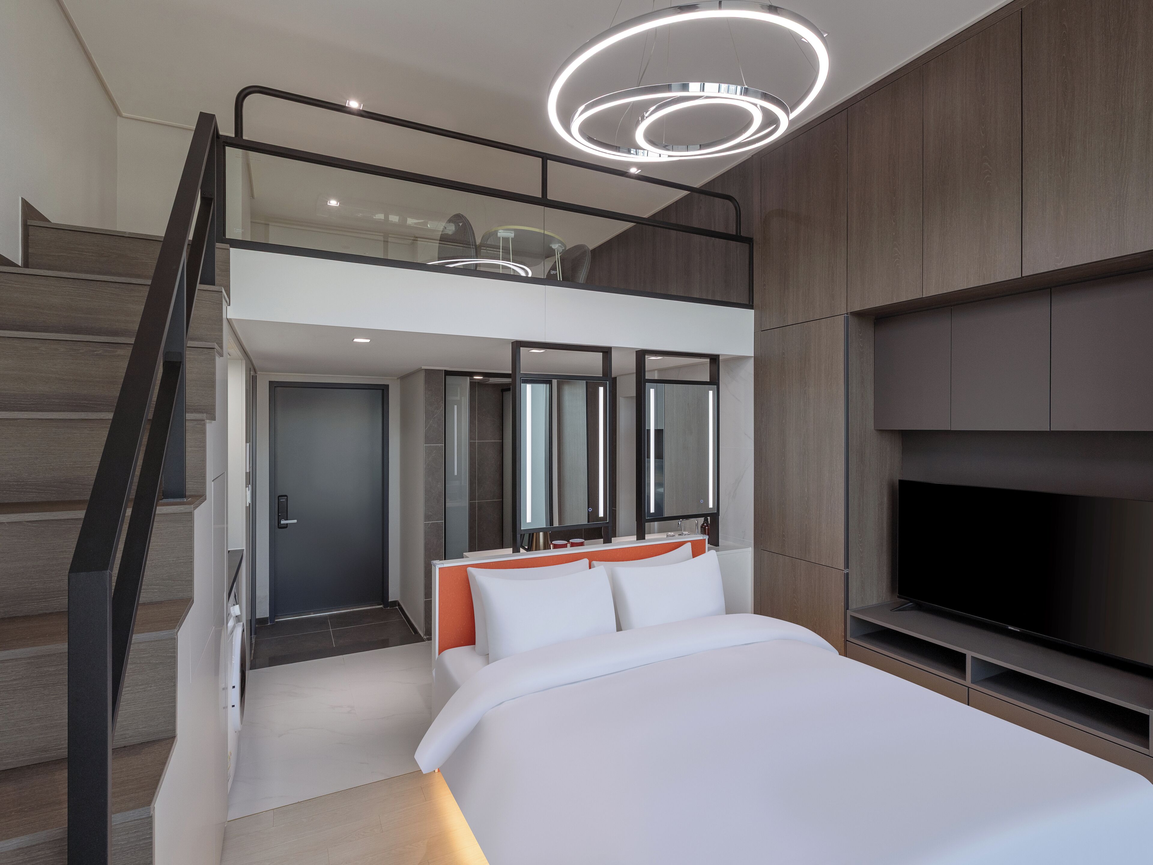 Un dormitorio moderno con una cama grande, un televisor y una escalera que lleva a un nivel superior.