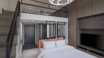 Un dormitorio moderno con una cama grande, un televisor y una escalera que lleva a un nivel superior.