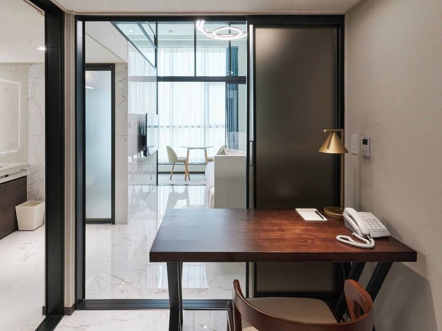 A modern hotel room with a wooden desk, a telephone, and a chair.