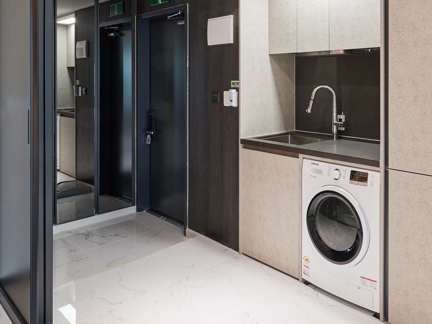 A modern bathroom with a marble floor, a washing machine, and a sink with a faucet.