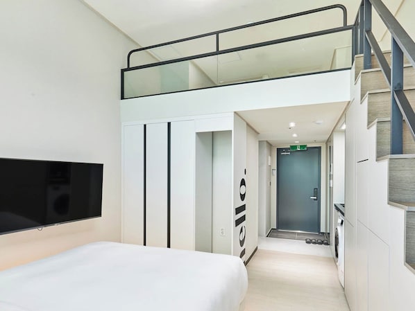 A modern hotel room with a bed, a TV, a wardrobe, and a staircase leading to an upper level. - NEWCZ CENTUM HOTEL (Busan)