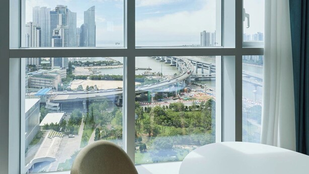 A modern hotel room with large windows offering views of a cityscape and a bridge. - NEWCZ CENTUM HOTEL (Busan)