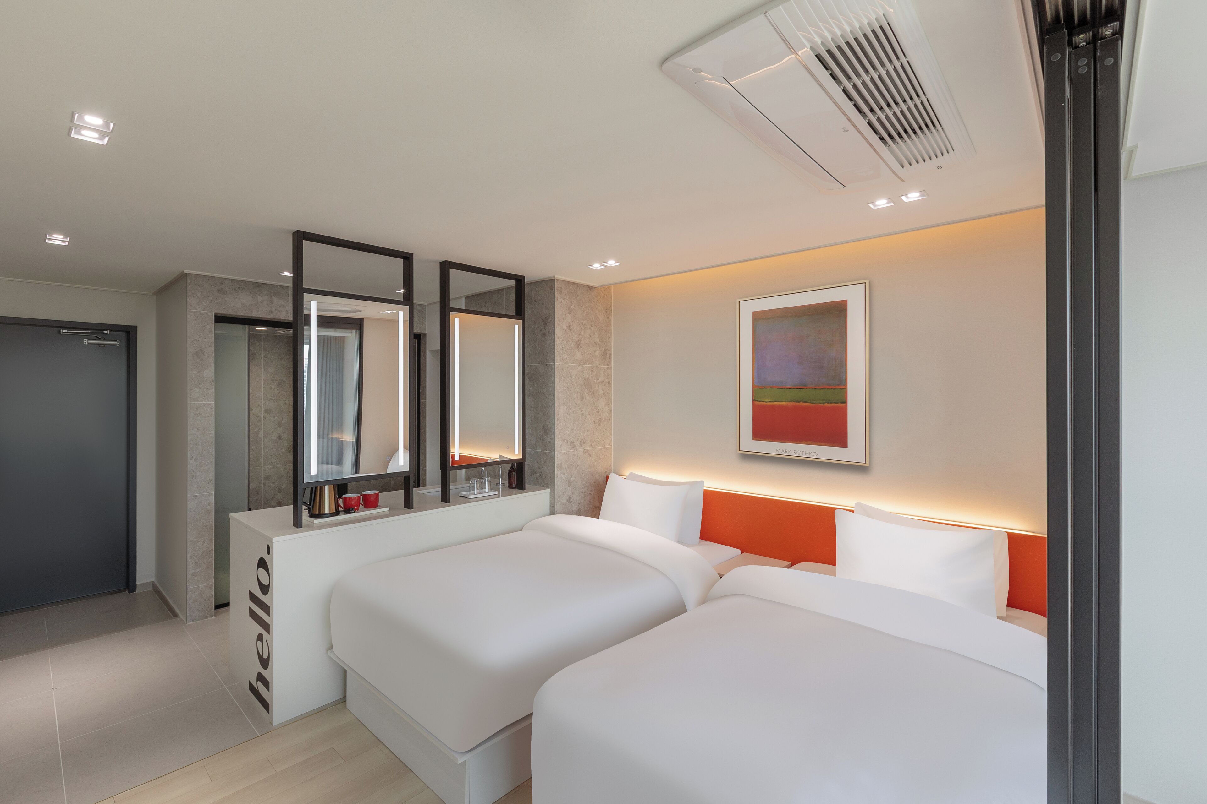 A modern hotel room with two beds, a large mirror, a painting on the wall, and a 'hello' sign on the door.