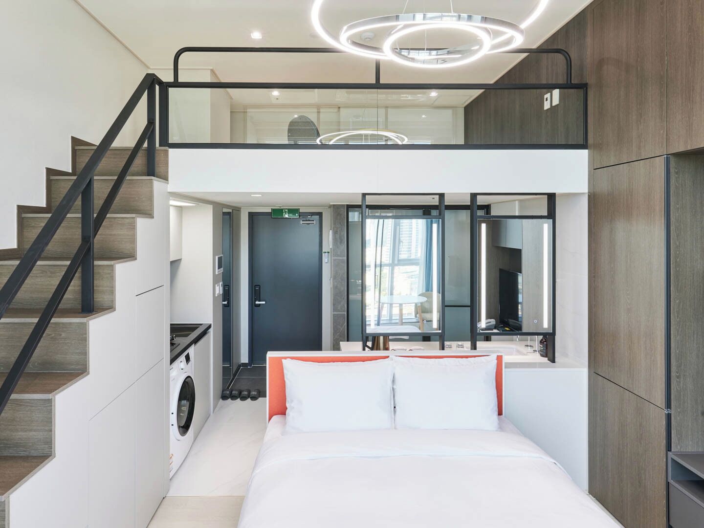 Une chambre d’hôtel moderne équipée d’un lit, d’un lave-linge, d’un escalier et offrant une vue sur la ville.
