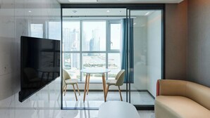 A modern living room with a flat-screen TV, a round coffee table, and a sofa. - NEWCZ CENTUM HOTEL (Busan)