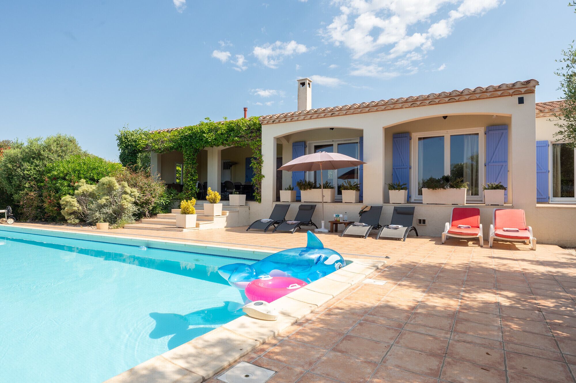 A pool area with lounge chairs and a covered seating area.
