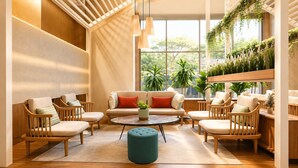 A modern living room with a sofa set, wooden chairs, a round coffee table, and a green ottoman.