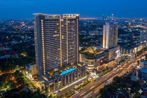 Un hotel de gran altura con varios pisos, una piscina en la azotea y vistas panorámicas de la ciudad.
