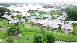 A resort with multiple bungalow-style buildings, a central swimming pool, and lush greenery.