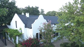A white building with a black roof, surrounded by greenery and a paved pathway. - Vendome Wine Estate (Paarl)