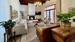 A spacious living room with a fireplace, comfortable seating, and large windows. - Vendome Wine Estate (Paarl)