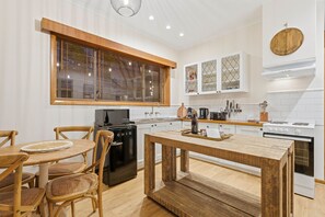 Una cocina moderna con comedor, muebles de madera y armarios blancos.