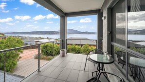 A balcony with a table and chairs, overlooking a body of water and distant mountains. - 4 Bedroom House - Gorgeous View (Tranmere)