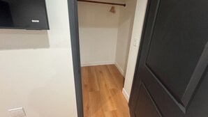 A narrow hallway with wooden flooring, a black door on the right, and a white wall with a small light switch. - Charming 2-bedroom house with WiFi, AC in welcoming Long Beach (Long Beach)