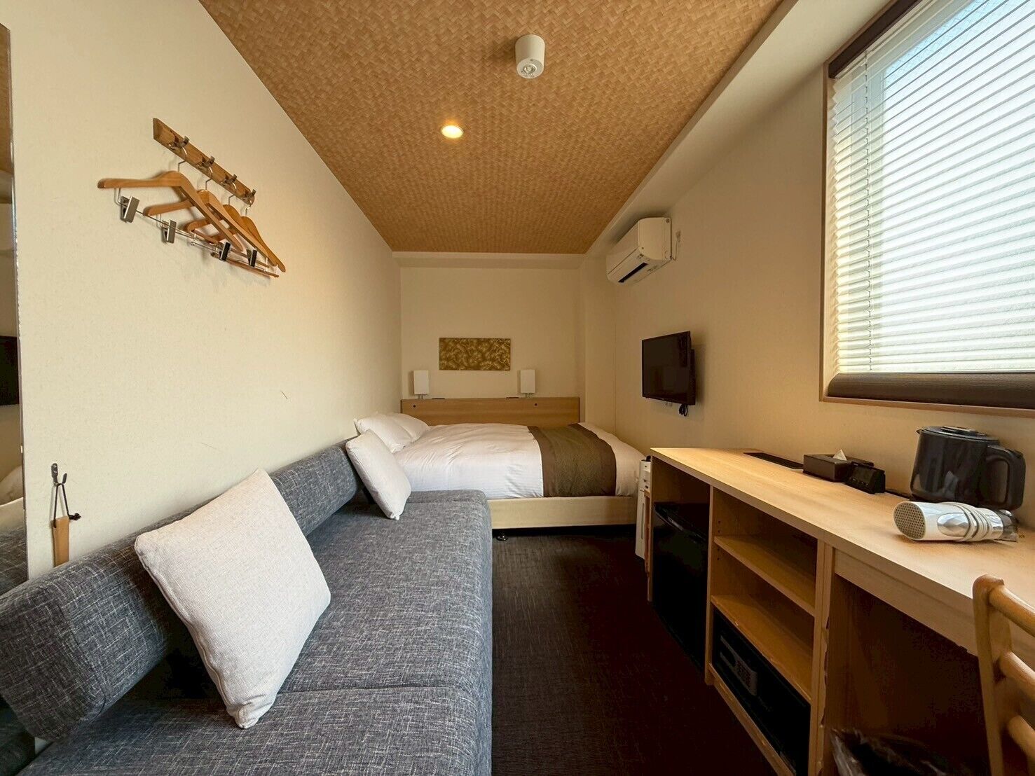 Une chambre d’hôtel de taille réduite, comprenant un lit, un canapé, un bureau et un téléviseur.