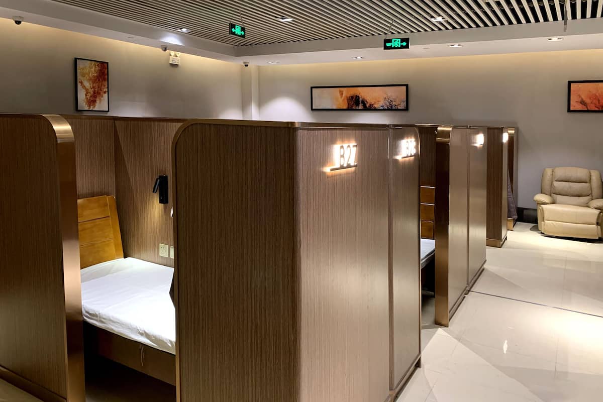 A hotel room with a wooden partition, a bed, a chair, and a small table.