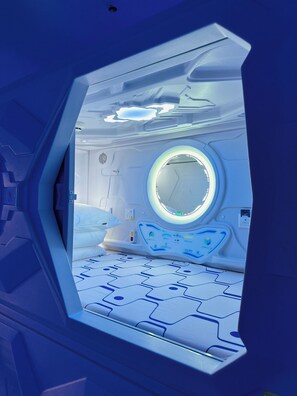 Una habitación futurista con un ventanal circular, una cama y un panel de control.