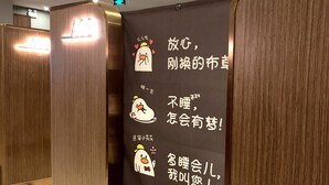 Eine Toilette mit Holzwänden und einer Wand mit Zeichentrickfiguren und Text.