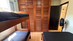 Una habitación con dos literas, un armario con puertas empañadas, un ventilador de techo y una ventana.