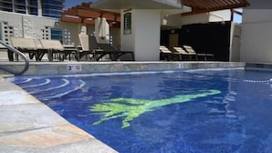 Una piscina con sillas de descanso y una zona techada.
