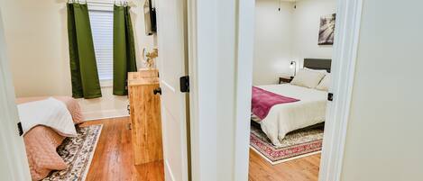 Ein Schlafzimmer mit zwei Betten, einem Deckenventilator und einem Fenster mit grünen Vorhängen.