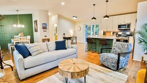 A modern living room with a grey sofa, patterned armchairs, and a wooden coffee table. - Charming 3-bedroom house walkable to Covington Square (Covington)