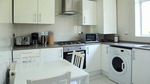 A compact kitchen with a stove, microwave, toaster, and washing machine.