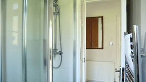 A modern bathroom with a glass shower enclosure, a wooden cabinet, and a white radiator.