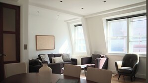 Un salon moderne avec un canapé sombre, une table ronde sur laquelle sont posés un livre et un vase, et un fauteuil en cuir.