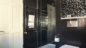 Une salle de bain moderne avec une douche à parois de verre, des toilettes et un mur recouvert de carreaux avec un motif décoratif.
