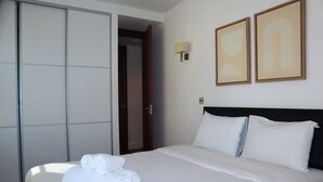 Une chambre d’hôtel avec un lit, une armoire et deux tableaux encadrés au mur.