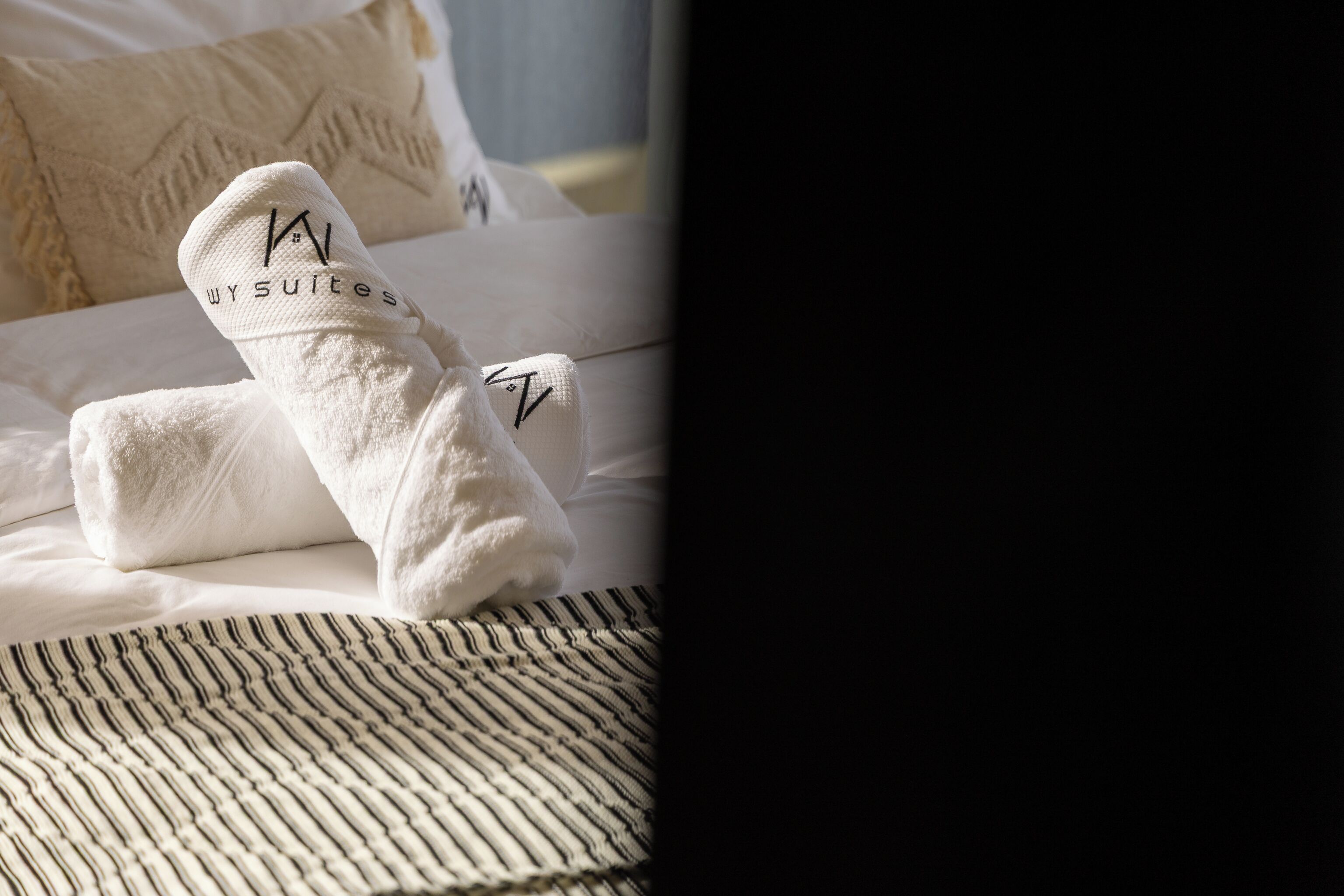 Un lit avec une literie blanche et une couverture à rayures.