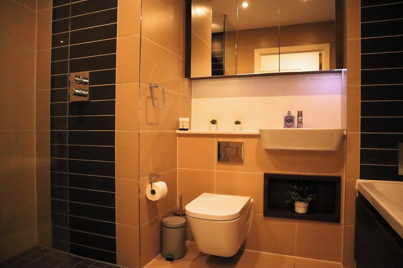 A modern bathroom with a toilet, sink, and mirror.