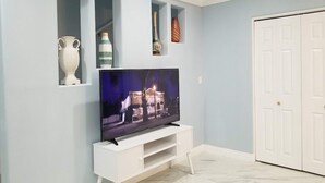 Una sala de estar con un televisor de pantalla plana sobre un soporte blanco, una puerta blanca y una pared azul claro.