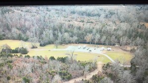 An aerial view of a campground with multiple RVs parked in a clearing surrounded by dense forest. - Perfect RV campground in Ravenden Springs for a peaceful getaway (Ravenden Springs)