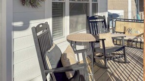 A covered outdoor seating area with a ceiling fan, a decorative wreath, and a sign that reads "A WAVE FROM IT ALL". - Amenities in this walk to Beach, New 3bed/3.5bath (Cape Charles)