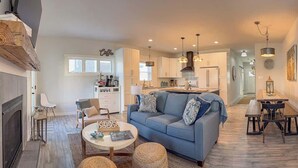 A spacious living room with a blue sofa, a fireplace, and a dining area with a wooden table and chairs. - Amenities in this walk to Beach, New 3bed/3.5bath (Cape Charles)