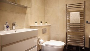 A modern bathroom with a white sink, a toilet, and a towel rack.