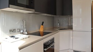 Una cocina moderna con microondas integrado, pileta de acero inoxidable y un bloque para cuchillos.
