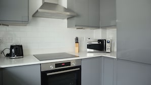 A modern kitchen with grey cabinets, a built-in oven, a toaster, and a microwave.
