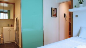 A hotel room with a bed, a bathroom, and a small kitchenette.