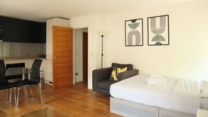 Een moderne woonkamer met een bank, een eettafel met stoelen en een keuken op de achtergrond.