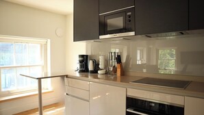 Een moderne keuken met een ingebouwde magnetron, koffiezetapparaat en messenblok.