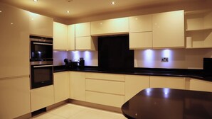 Una cocina moderna con armarios blancos, encimera negra y electrodomésticos integrados.