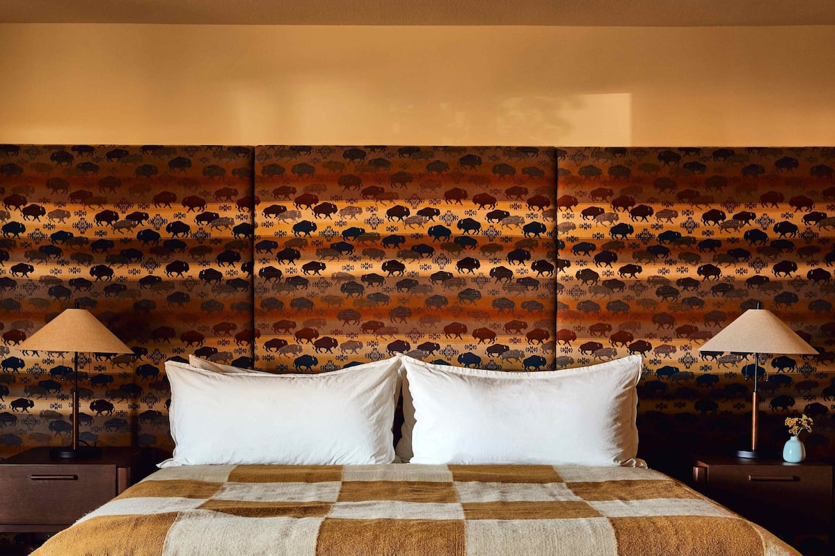 A hotel room with a large bed, two bedside tables, and a patterned headboard.