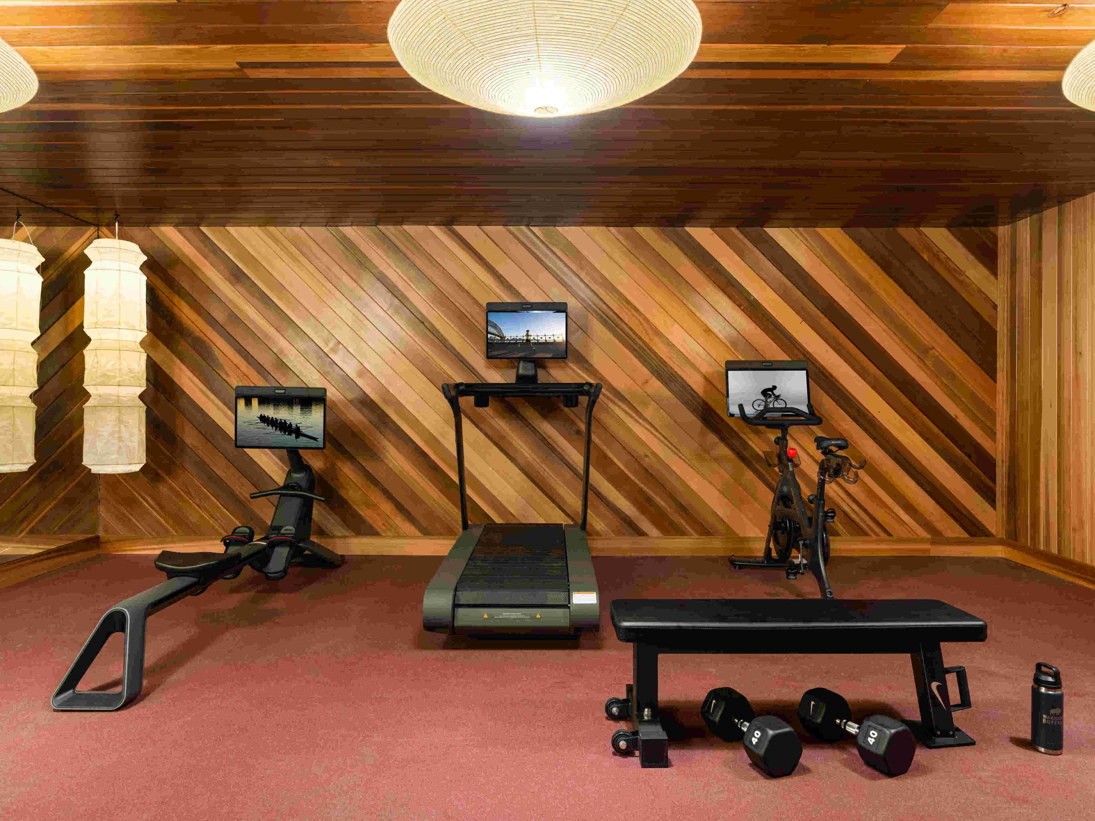 Een fitnessruimte met trainingsapparatuur, loopbanden en een bank.