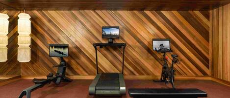 Een fitnessruimte met trainingsapparatuur, loopbanden en een bank.