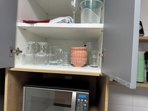 Kitchen essentials at your fingertips, including a microwave oven and ample storage for glassware.