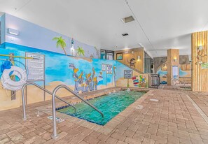 An indoor swimming pool with a mural, lifeguard stand, and safety signs.