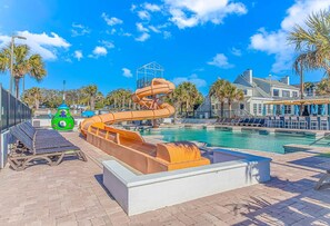 A pool area with a water slide, lounge chairs, and a pool.